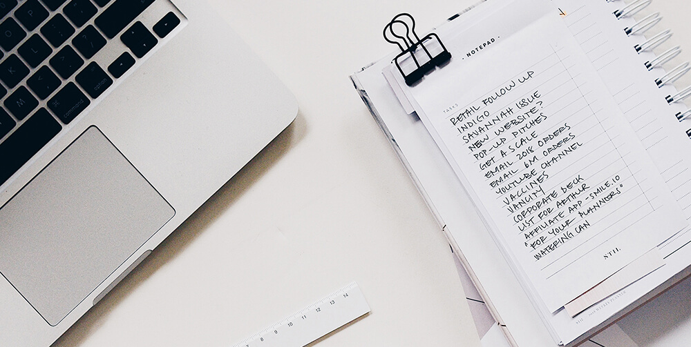 white notepad and laptop on table