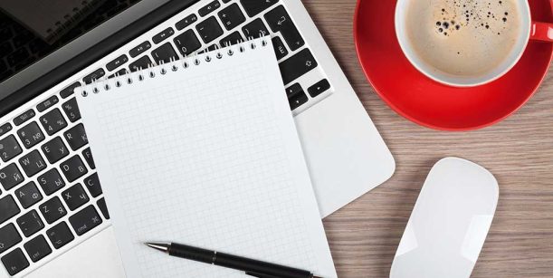 notepad, laptop, and coffee cup on desk