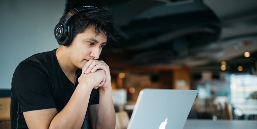 man wearing headphones and using laptop