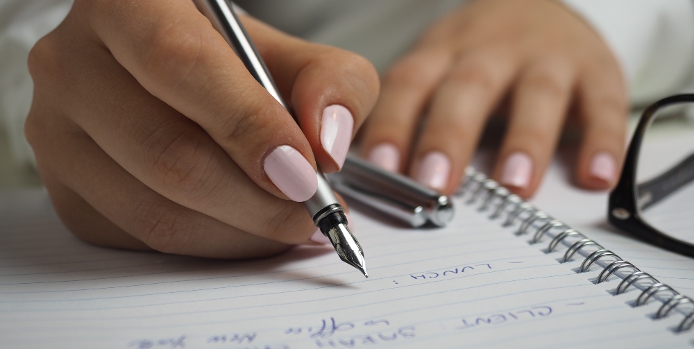 person holding pen and writing a list