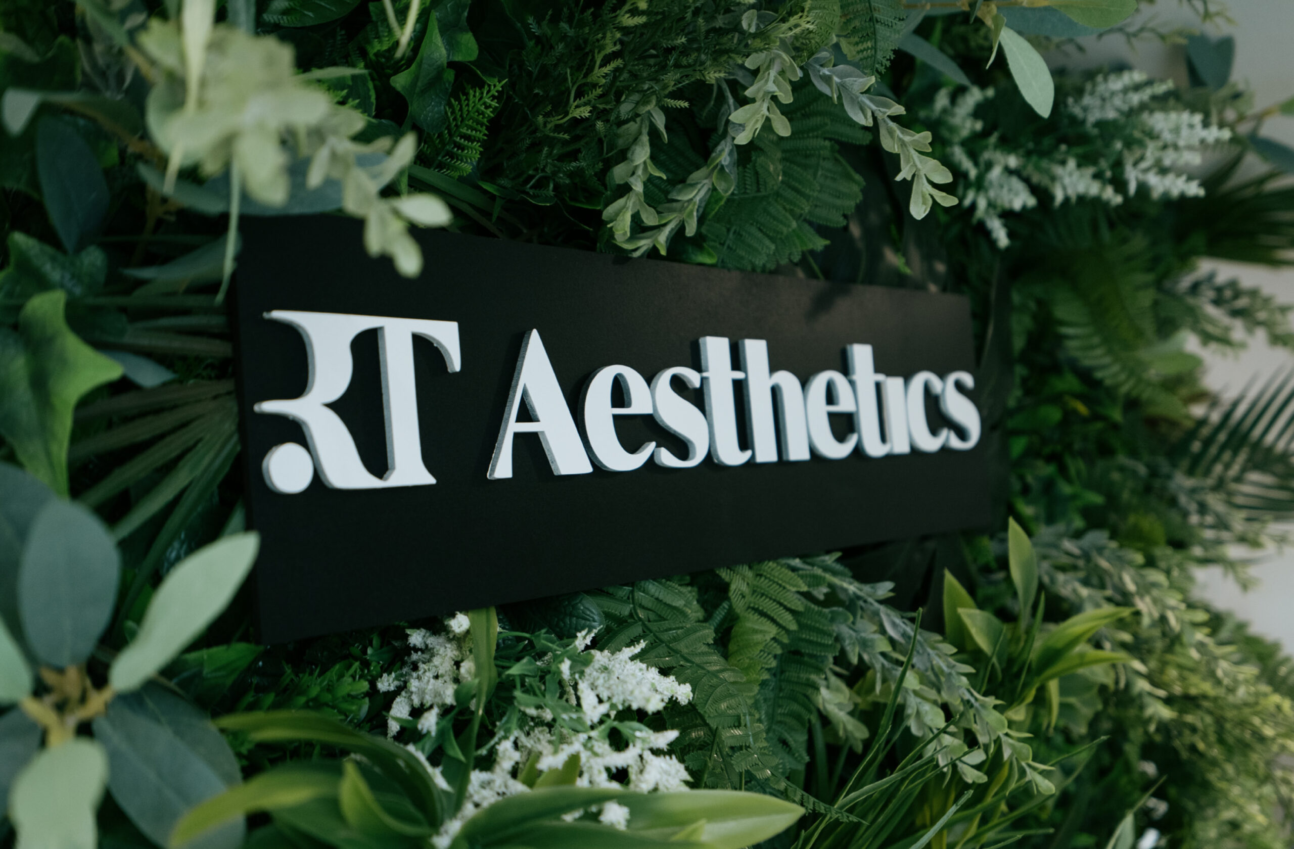 black RT Aesthetics plaque on background of flowers