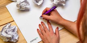 person writing and scrumpled up bits of paper